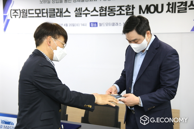 셀수스협동조합 안주엽이사장이 조합에서 발간된 책자를 월드모터클래스 권태현 대표에게 전달하고 있다.