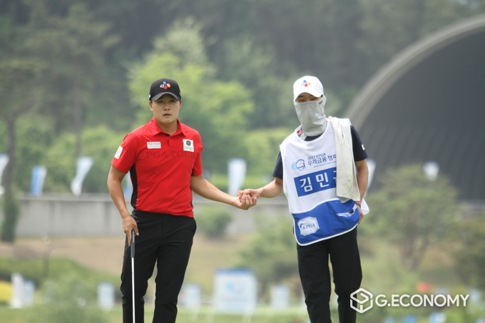 홀 주변 그린경사를 읽기 위해 눈을 떼지 않고 있는 김민규