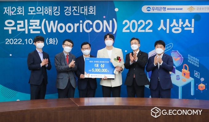 우리은행(은행장 이원덕)은 지난 18일 서울 중구 소재 우리은행 본점에서 제2회 모의해킹 경진대회 '우리콘(WooriCON) 시상식을 개최했다. 이원덕 우리은행장(왼쪽 세번째), 김철웅 금융보안원장(오른쪽 두번째), 김백수 우리은행 정보보호그룹 부행장(오른쪽 첫번째), 박춘식 아주대학교 교수(왼쪽 두번째), 박찬암 스틸리언 대표(왼쪽 첫번째)가 대상 수상자와 기념촬영을 하고 있다(사진=우리은행)