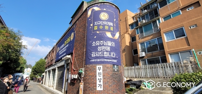 (가칭)신사동 지역주택조합 추진위원회 사무실이 위치한 무진상가에 지구단위계획 접수완료를 알리는 대형현수막이 게시됐다.