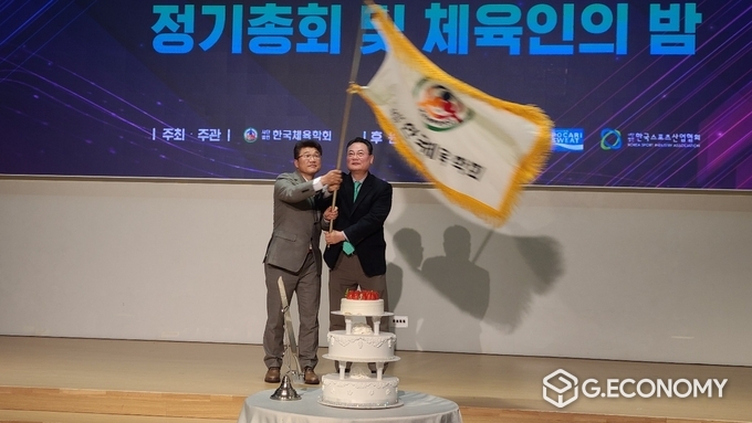 한국체육학회 깃발을 김도균 27대 회장이 이한경 신임회장에게 전달하고 있다, 뉴스아이이에스
