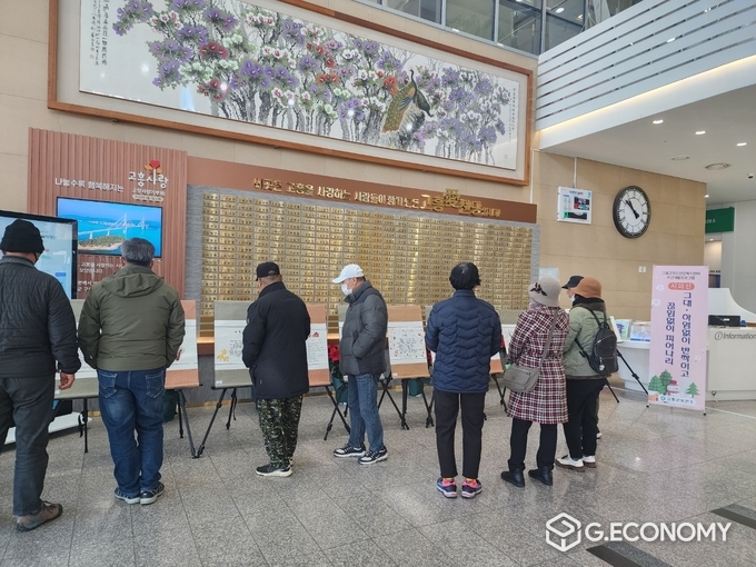 고흥군, 보건소 정신건강복지센터 회원 시화전 개최 (고흥군청 로비에서 관람객들이 보건소 정신건강복지센터 회원들의 시화전 작품을 보고있다.).고흥군 제공