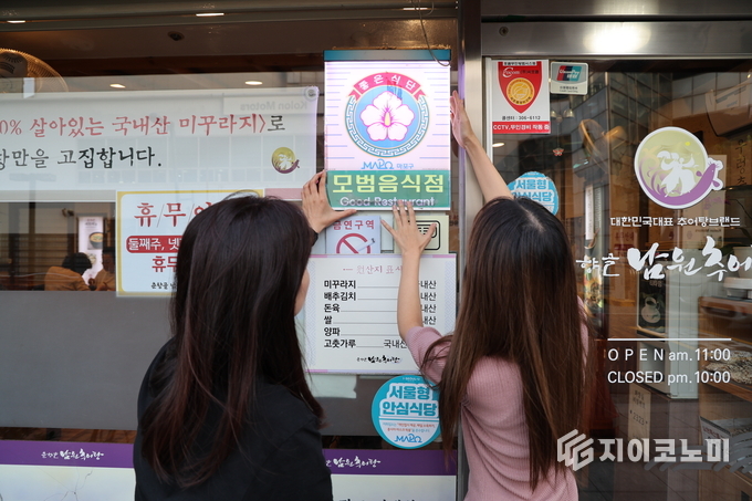 모범음식점으로 선정된 음식점에 모범음식점 표지판을 다는 모습. 마포구 제공.