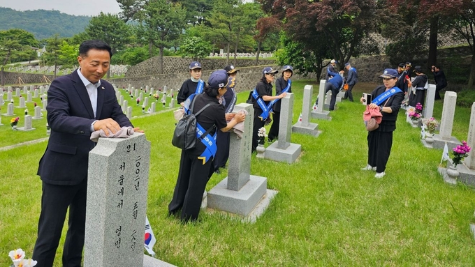 장영동 고양시장애인체육회 사무국장과 행사 참가자들이 현충원 묘역 정화 활동을 진행하고 있다. (사진=고양시장애인체육회)