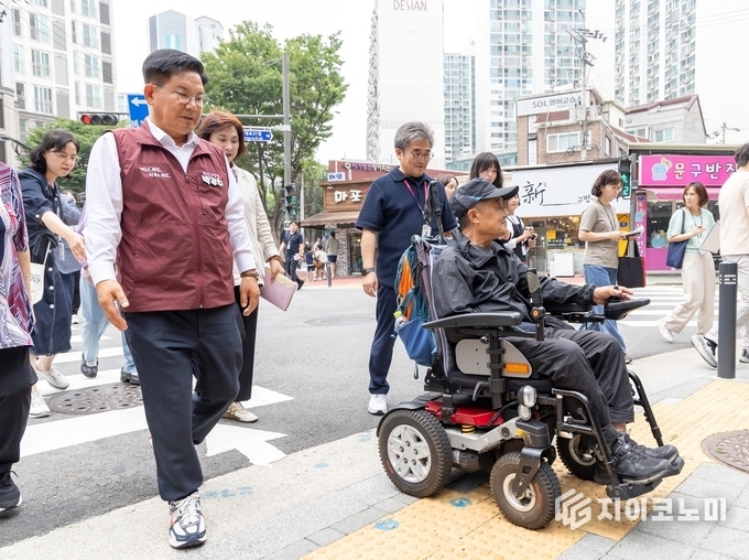박강수 마포구청장이 휠체어를 탄 주민과 함께 새로 조성된 무장애길을 걷고 있다.