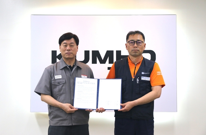 김명선 금호타이어 생산기술총괄 부사장과 황용필 금호타이어지회 대표 지회장이 노사 특별합의문을 들고 기념 촬영을 하고 있다. 금호타이어 제공