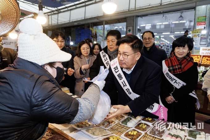 박강수 마포구청장이 아현시장에서 떡을 구매하고 있다.