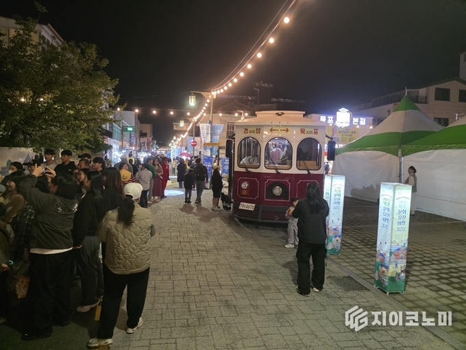 근대 트롤리버스에 탑승한 시민들이 1930년대 경성 복식 체험과 함께 목포 근대역사거리 야경을 둘러보며 특별한 밤 여행을 즐기고 있다. G이코노미DB