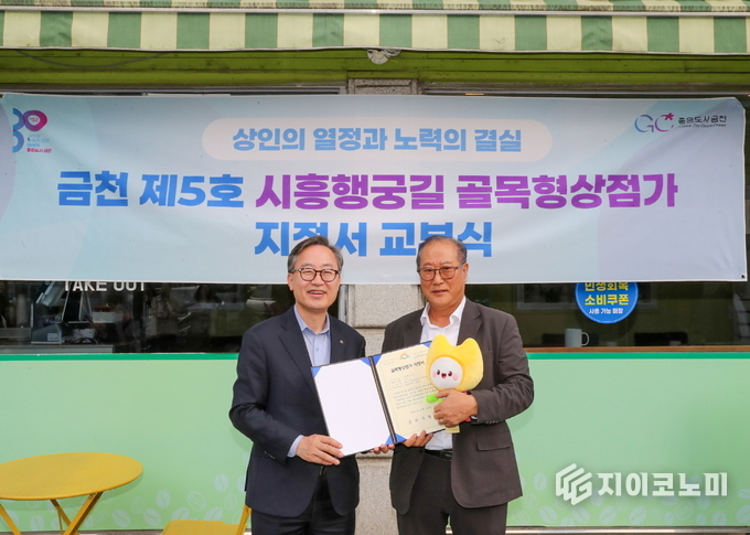 유성훈 금천구청장(왼쪽)과 김명식 상인회장이 골목형상점가 지정서 교부식을 진행하고 기념촬영을 하고 있다.