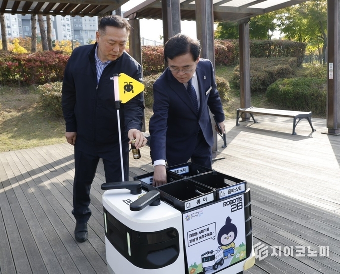 진교훈 서울 강서구청장(오른쪽)이 마곡하늬공원에서 열린 ‘AI 기반 자율주행 로봇서비스 실증 시연회’에서 빈 캔을 수거함에 넣고 있다.