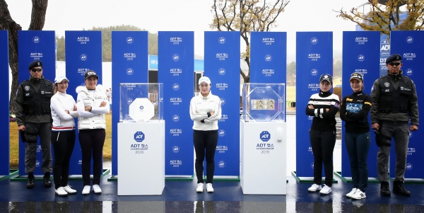 (좌측부터) 배선우, 이정은6, 지한솔, 최혜진, 오지현이 트로피와 머니박스 옆에서 포즈를 취하고 있고, ADT캡스 경호원들이 이를 지키고 있다