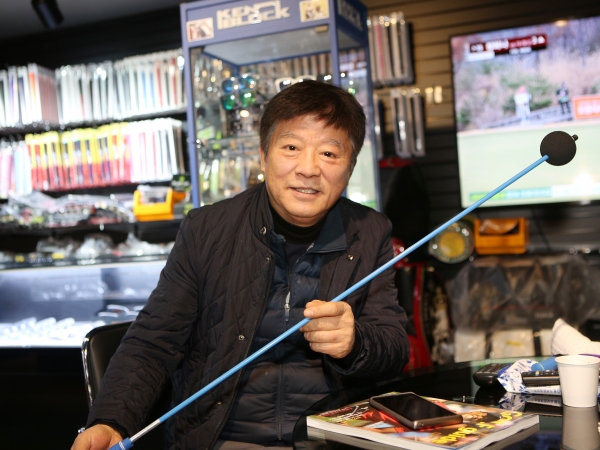 서한석 대표의 아버지인 서재선 프로가 아들과 함께 개발한 스윙연습기를 들고 설명하고 있다.