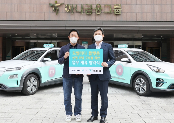하나은행은 지난 13일 서울 중구에 위치한 하나금융그룹 명동 본점에서 모빌리티 산업을 성장시키는 상생 모델 구축을 위한 업무협약을 체결했다고 밝혔다. 이행열 케이에스티모빌리티 대표(사진왼쪽)와 이장성 하나은행 플랫폼금융사업TFT 본부장이 마카롱택시 앞에서 기념촬영을 하고 있다.